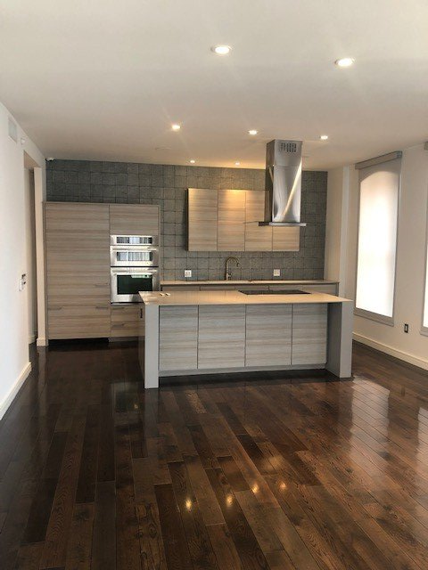 An empty kitchen with hardwood floors and a large island