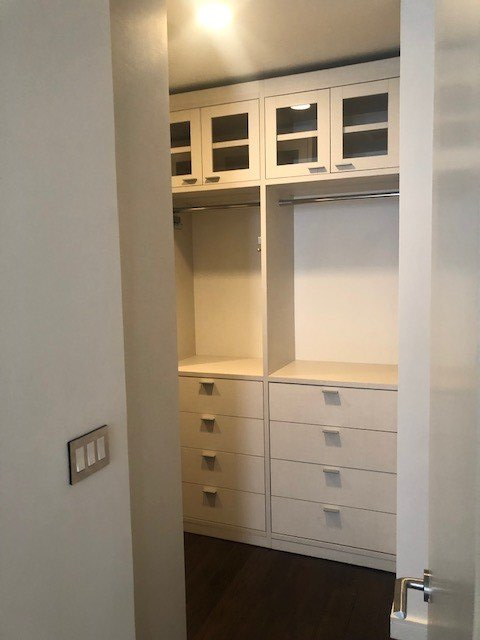 A walk in closet with white cabinets and drawers