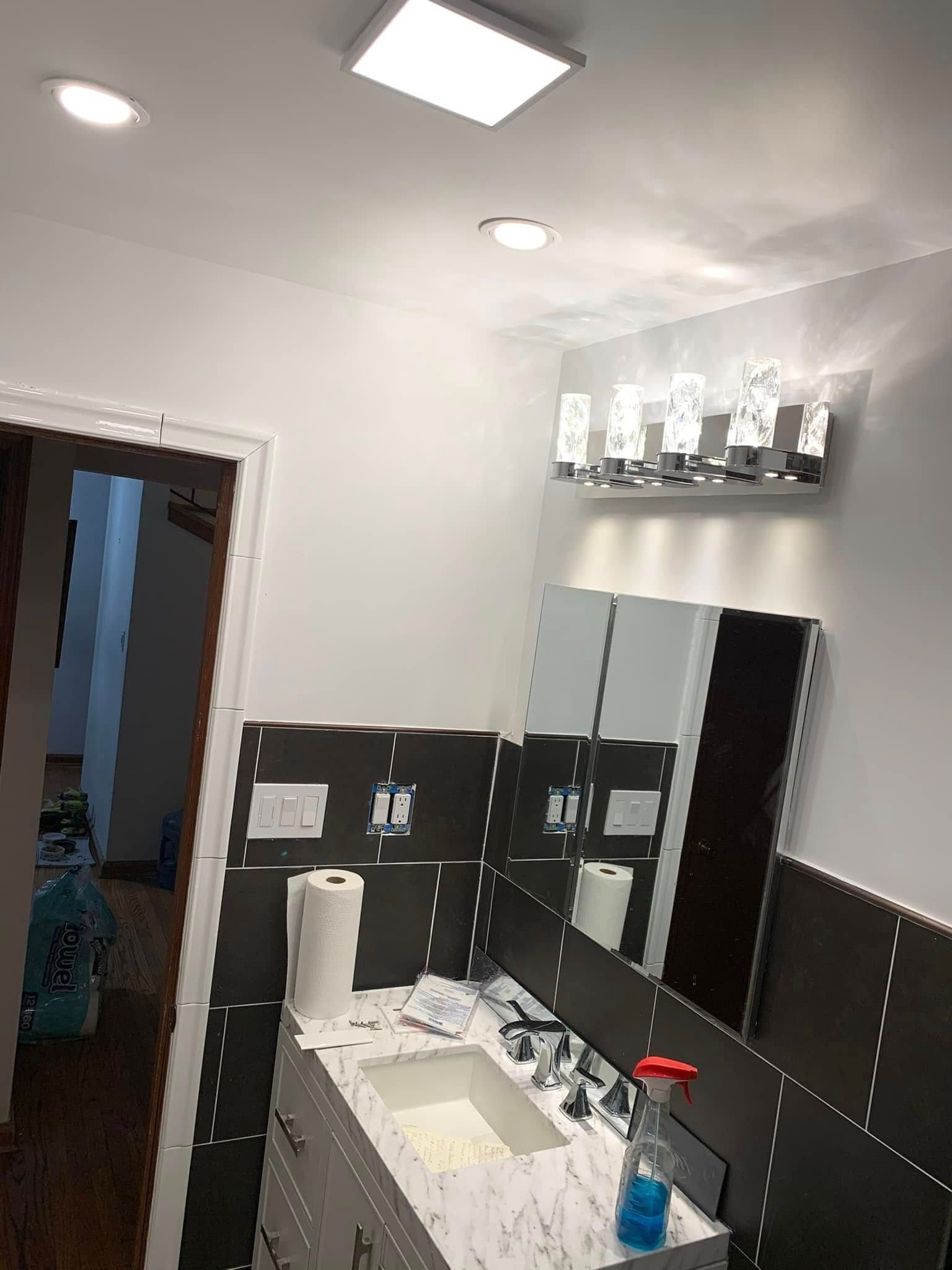 Bathroom with a sink, mirror, and overhead lights.