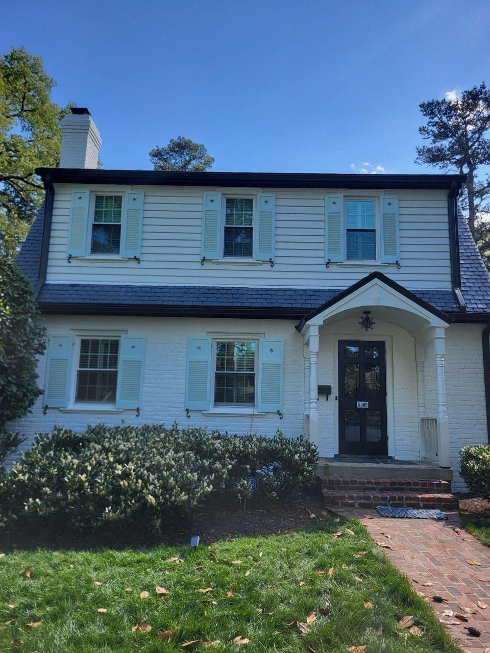 A white house with blue shutters and a black door