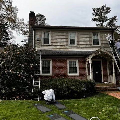 A group of people are painting a brick house.