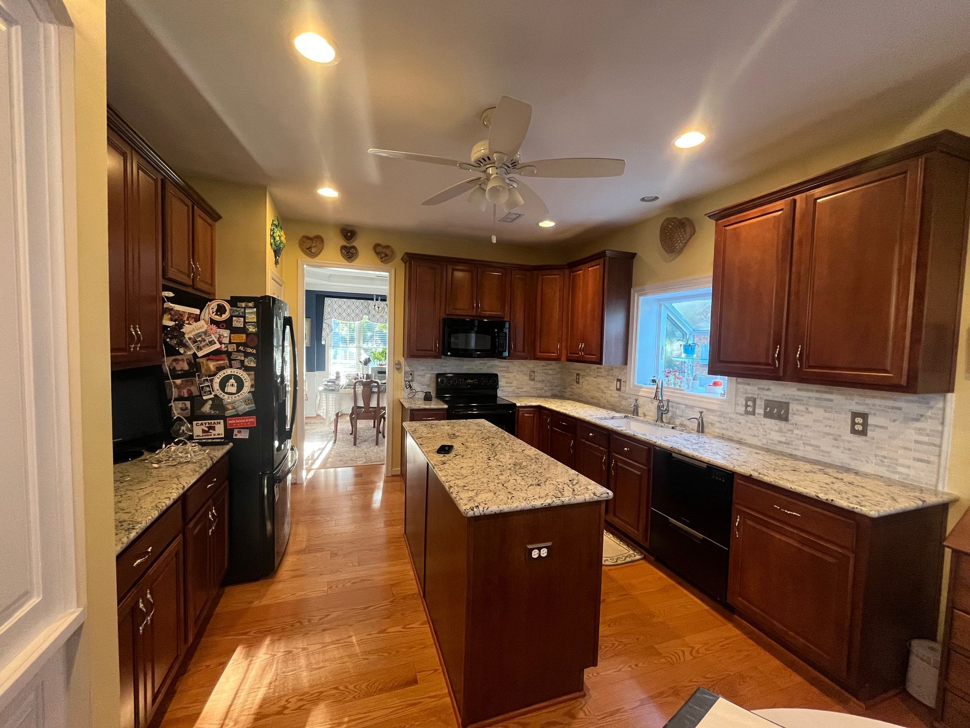 A kitchen with wooden cabinets, granite counter tops, and a ceiling fan.