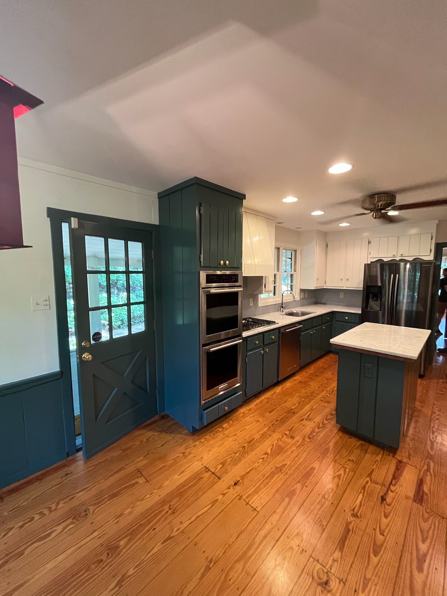 A kitchen with wooden floors, blue cabinets, stainless steel appliances and a large island.