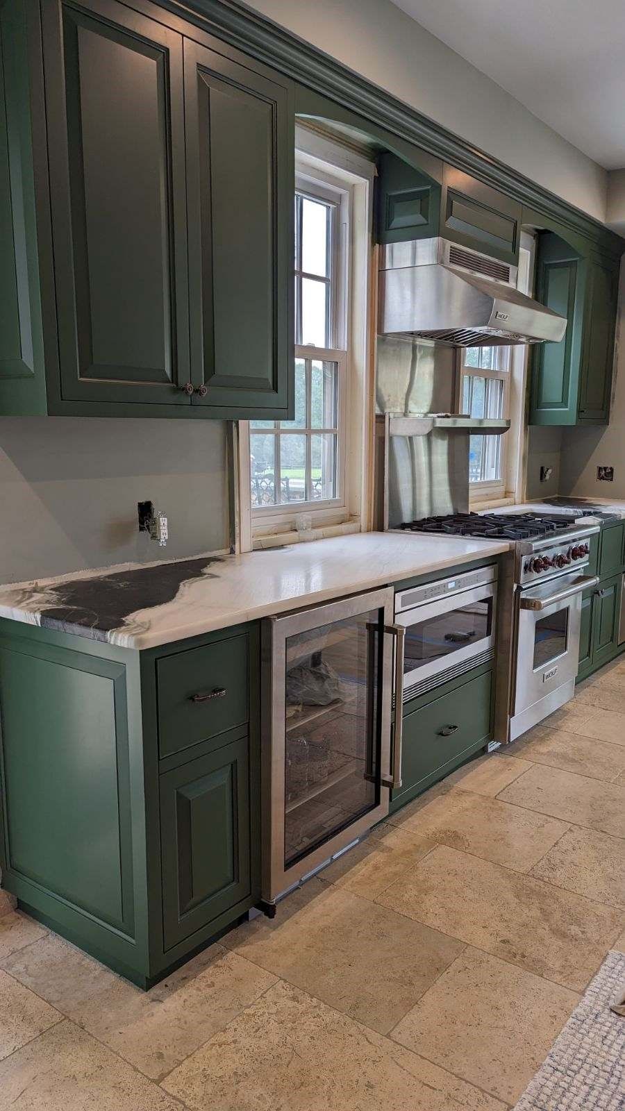 A kitchen with green cabinets and stainless steel appliances.