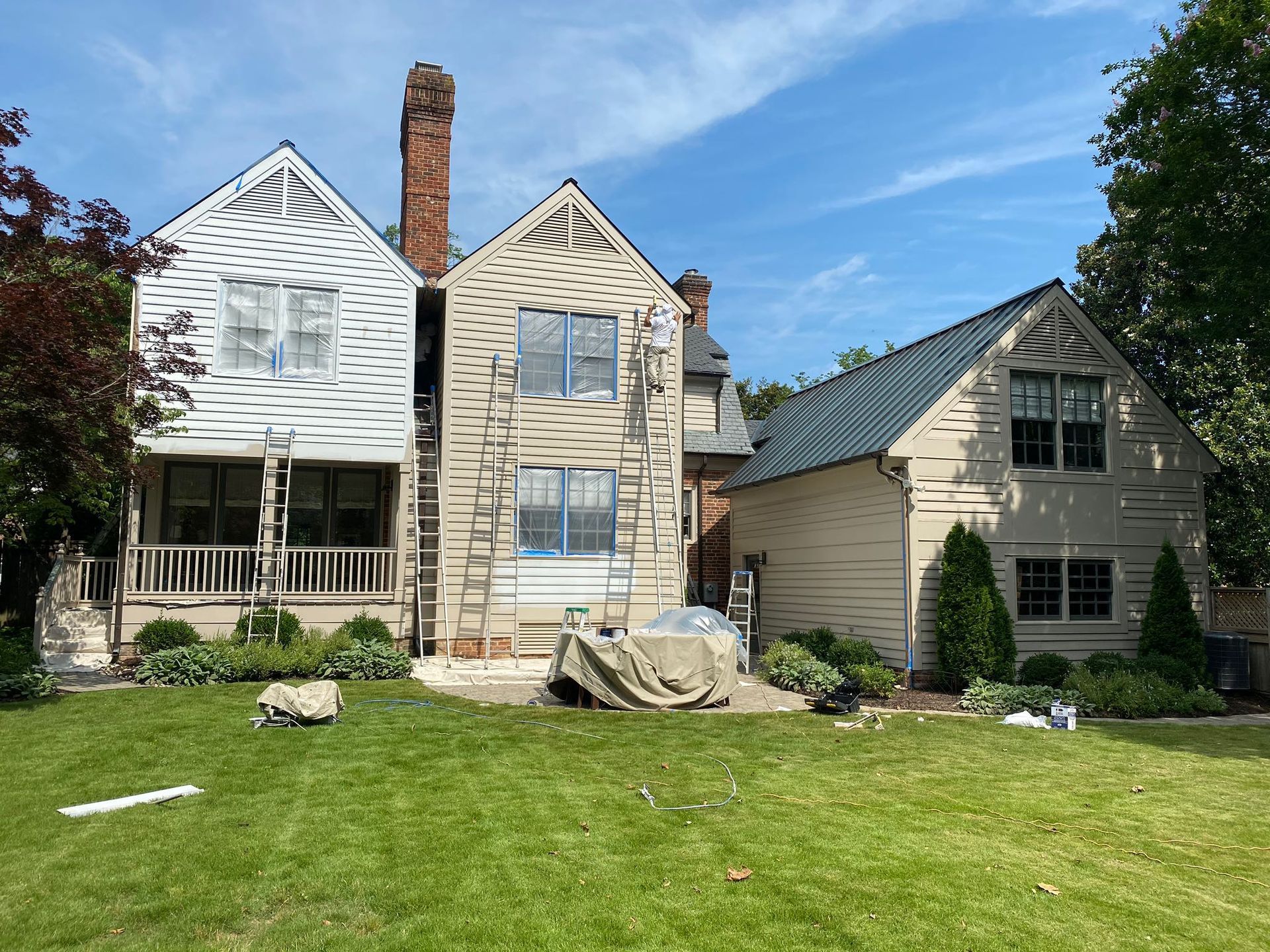 A house is being painted with a ladder in the backyard.