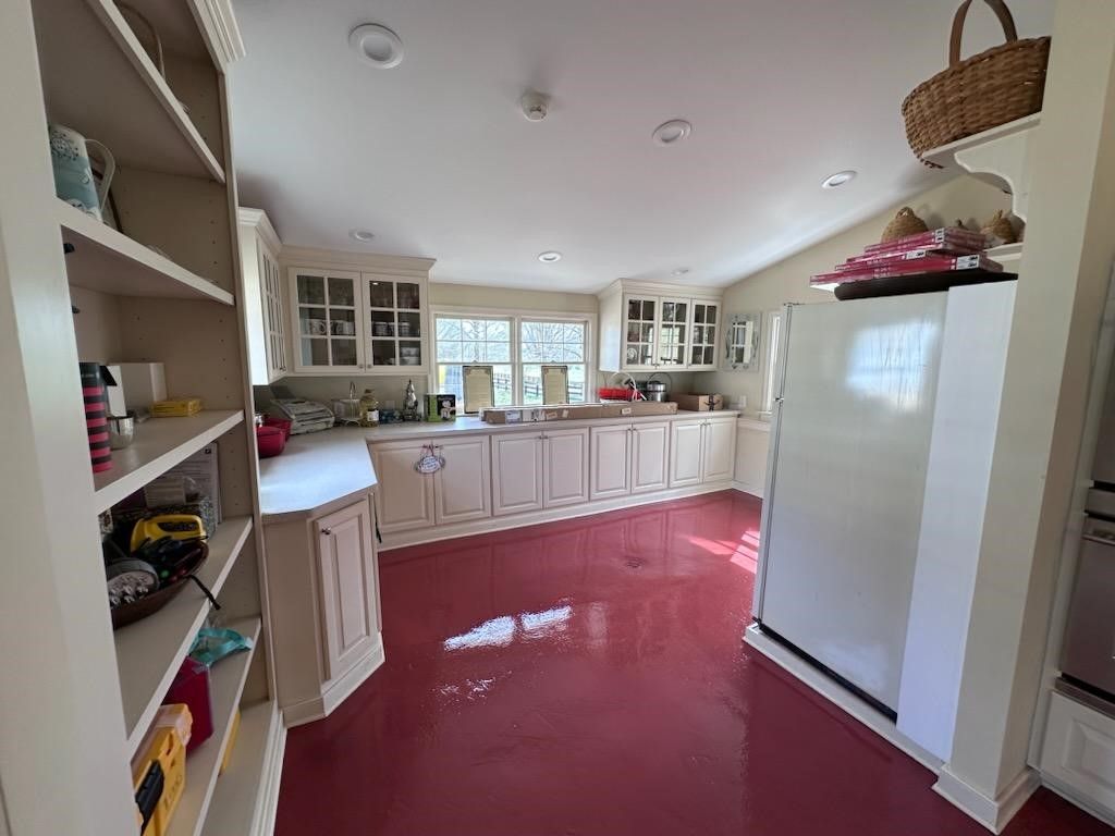 A kitchen with white cabinets and a red floor