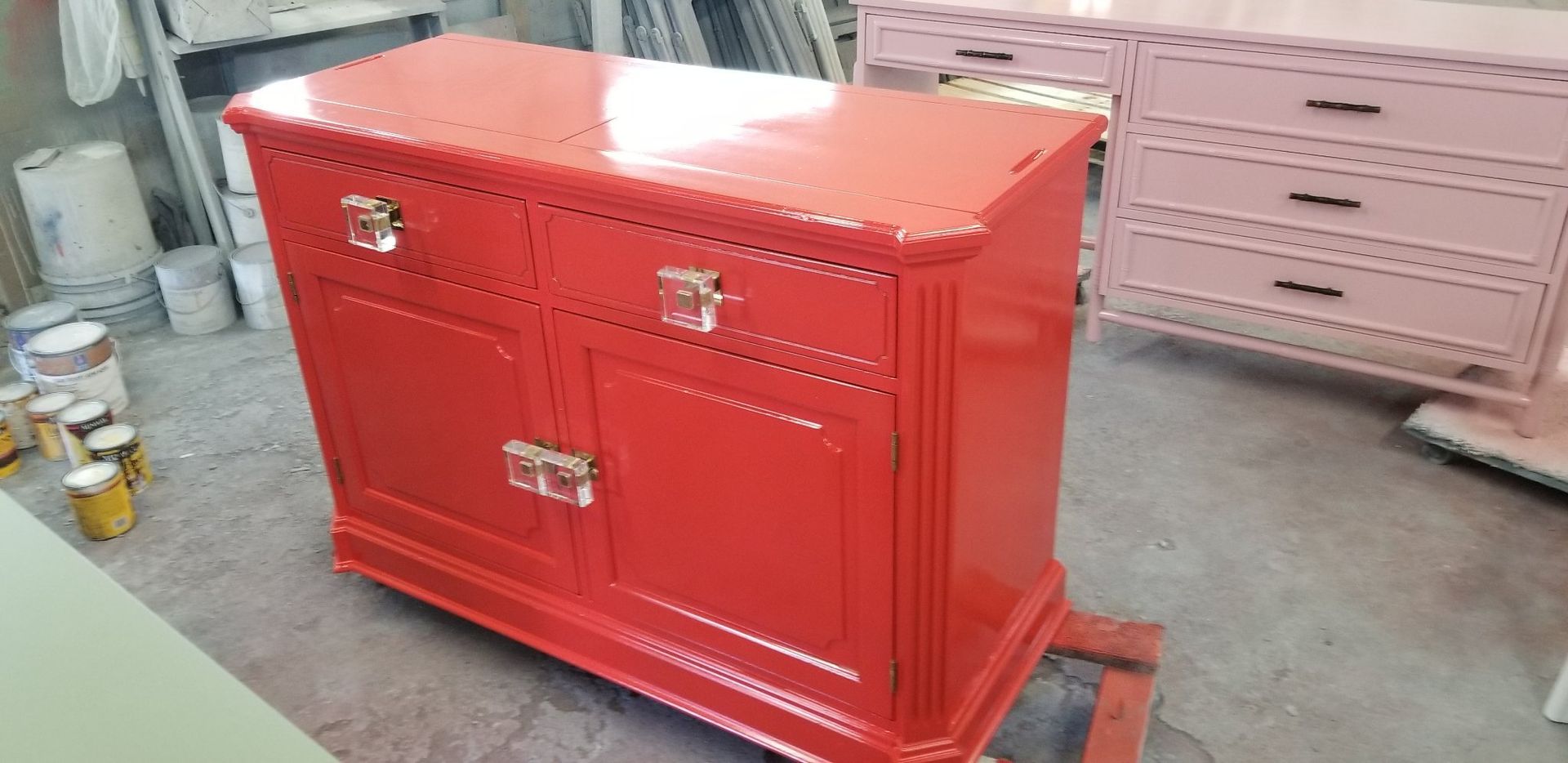 A red dresser is sitting in a room next to a pink dresser.