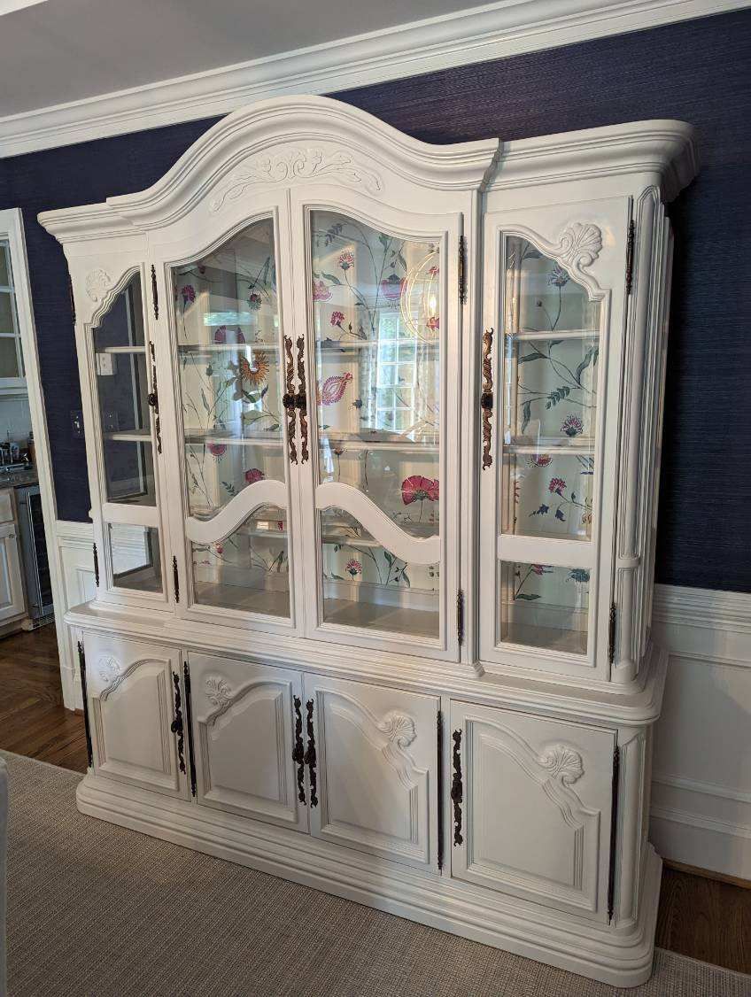 A white hutch is sitting in a dining room next to a blue wall.