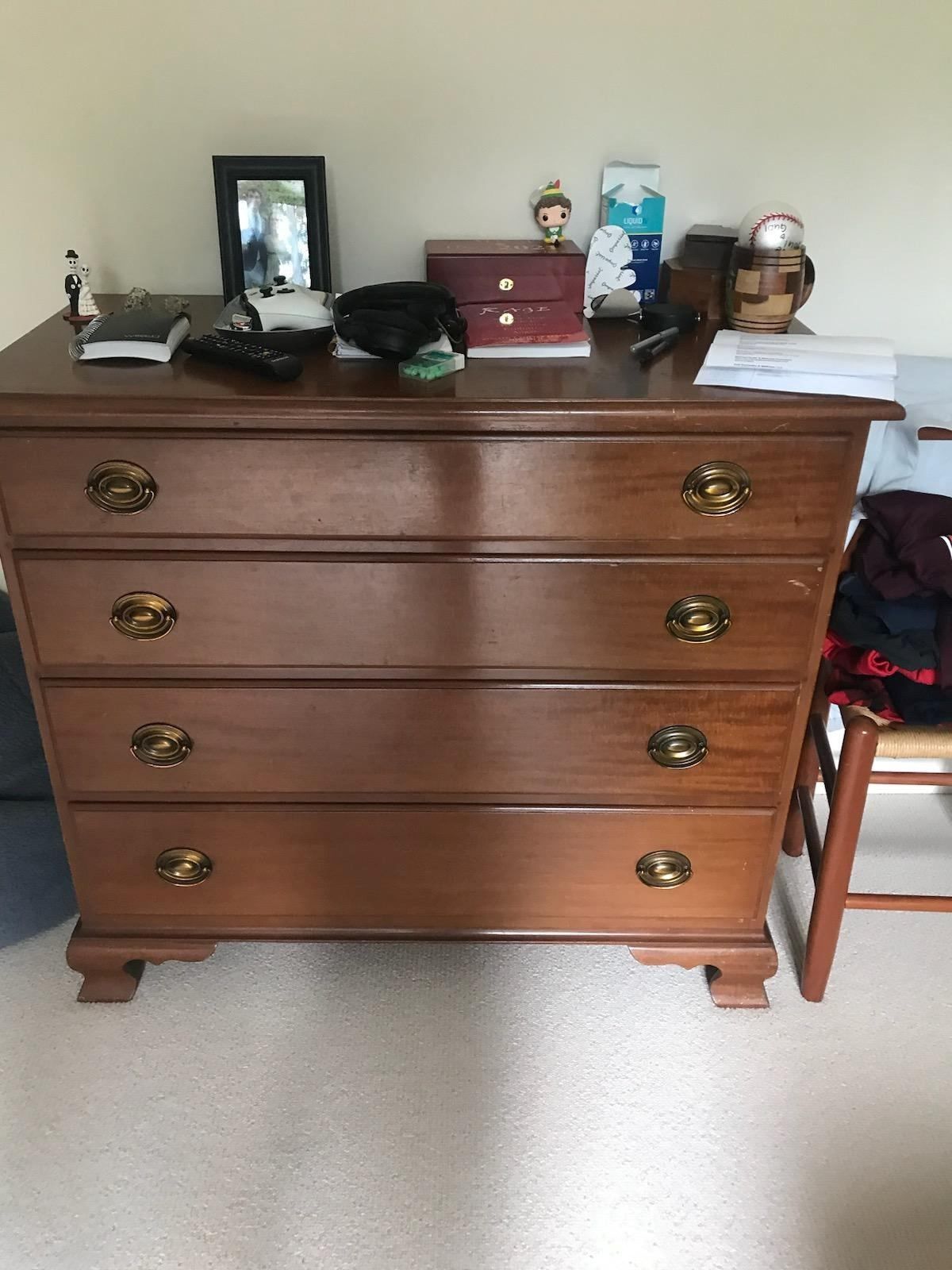 A wooden dresser with four drawers in a bedroom