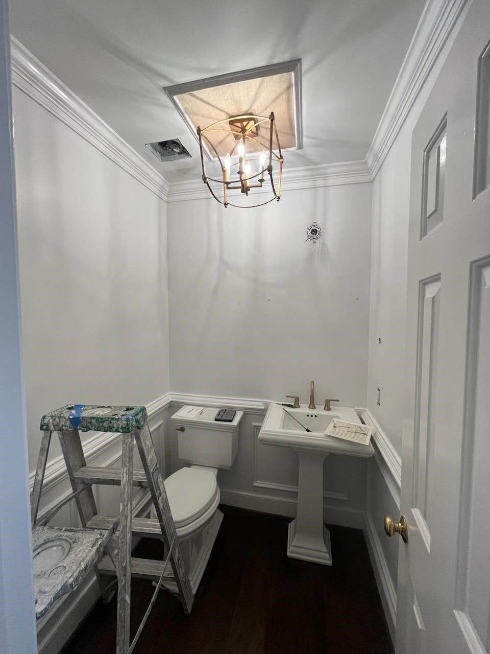 A bathroom with a toilet, sink and ladder