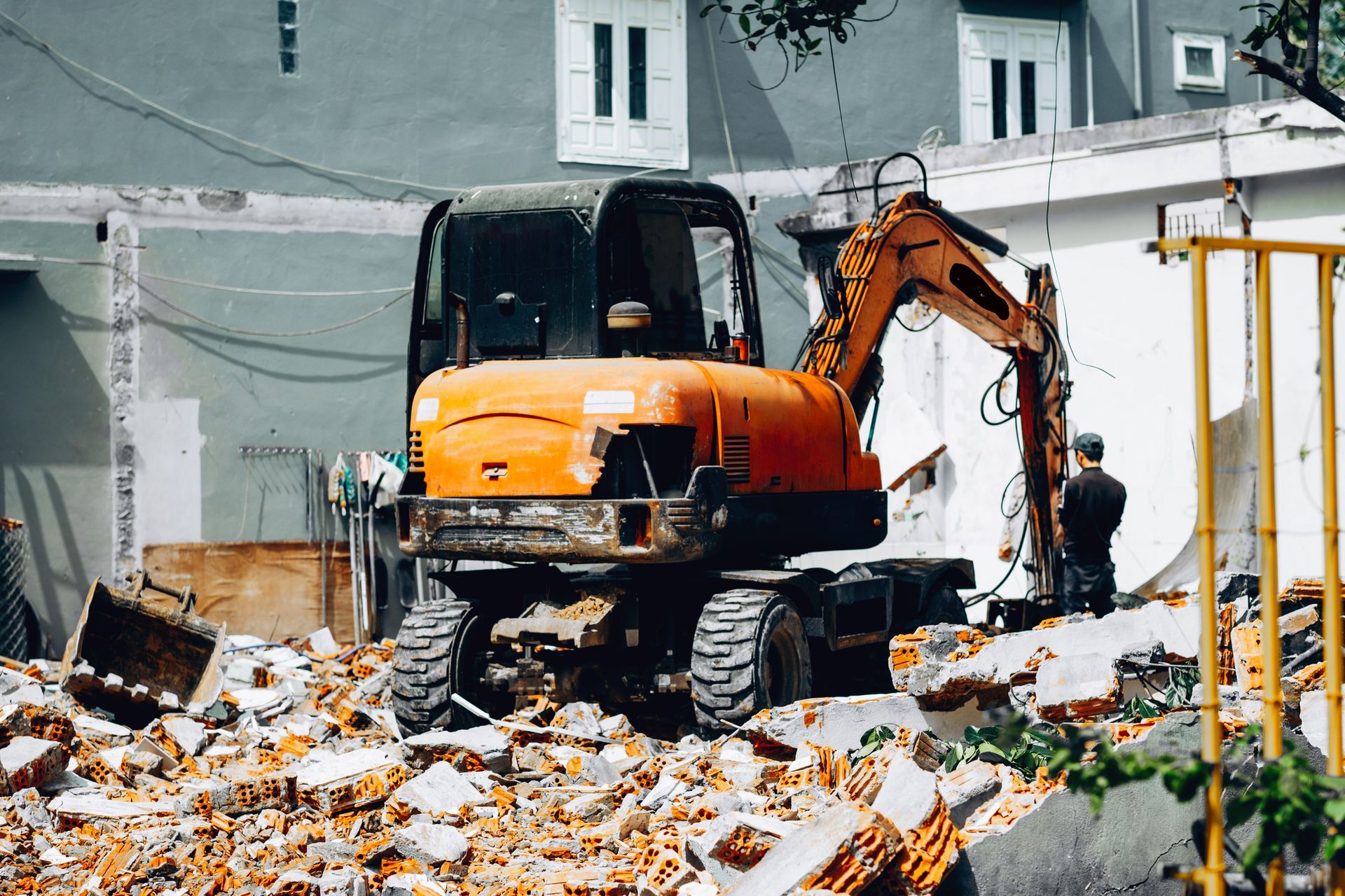 An orange excavator clearing rubble at a demolition site.