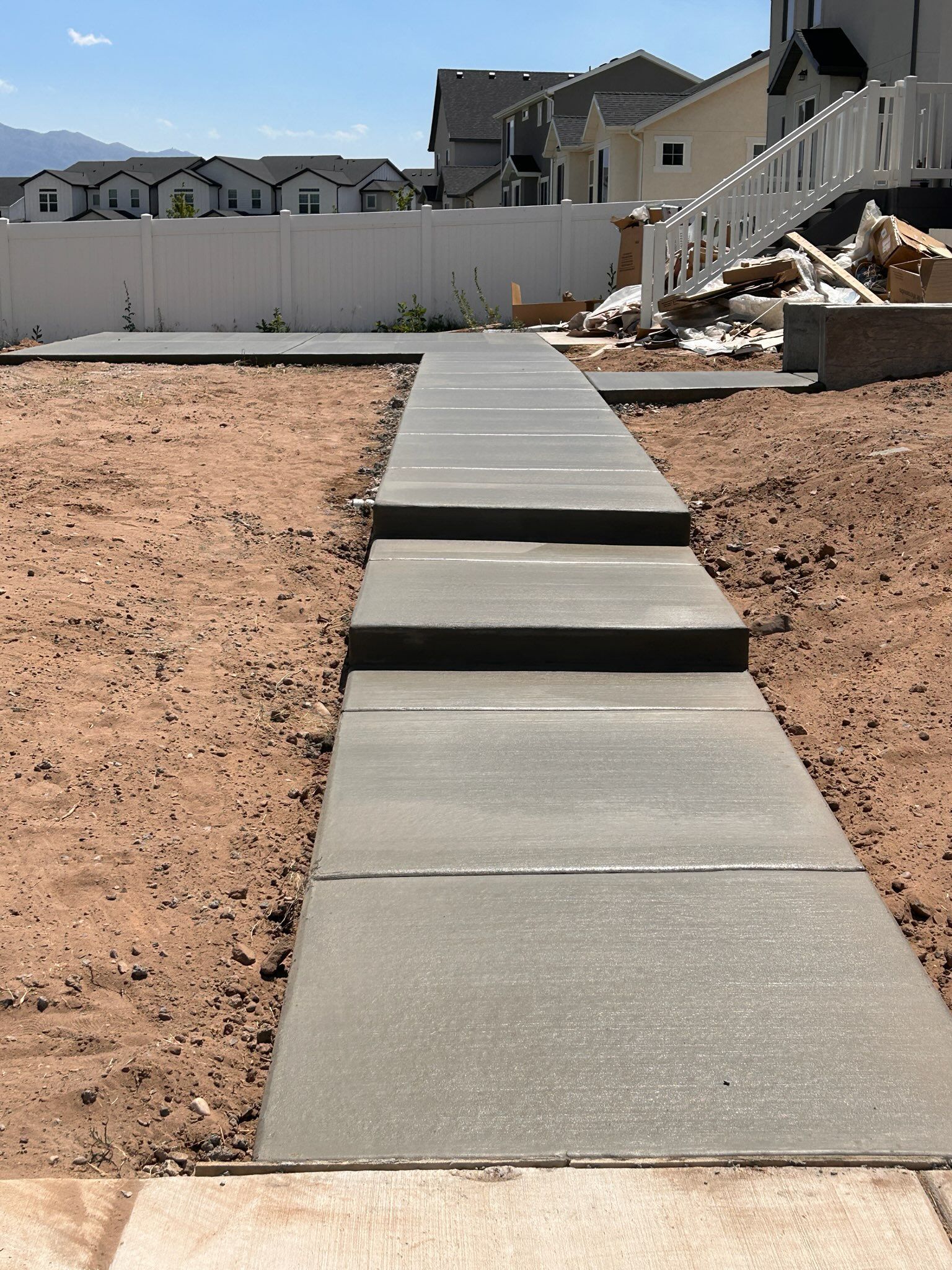 Woman in straw hat smiles, holding wine glass near a lake.