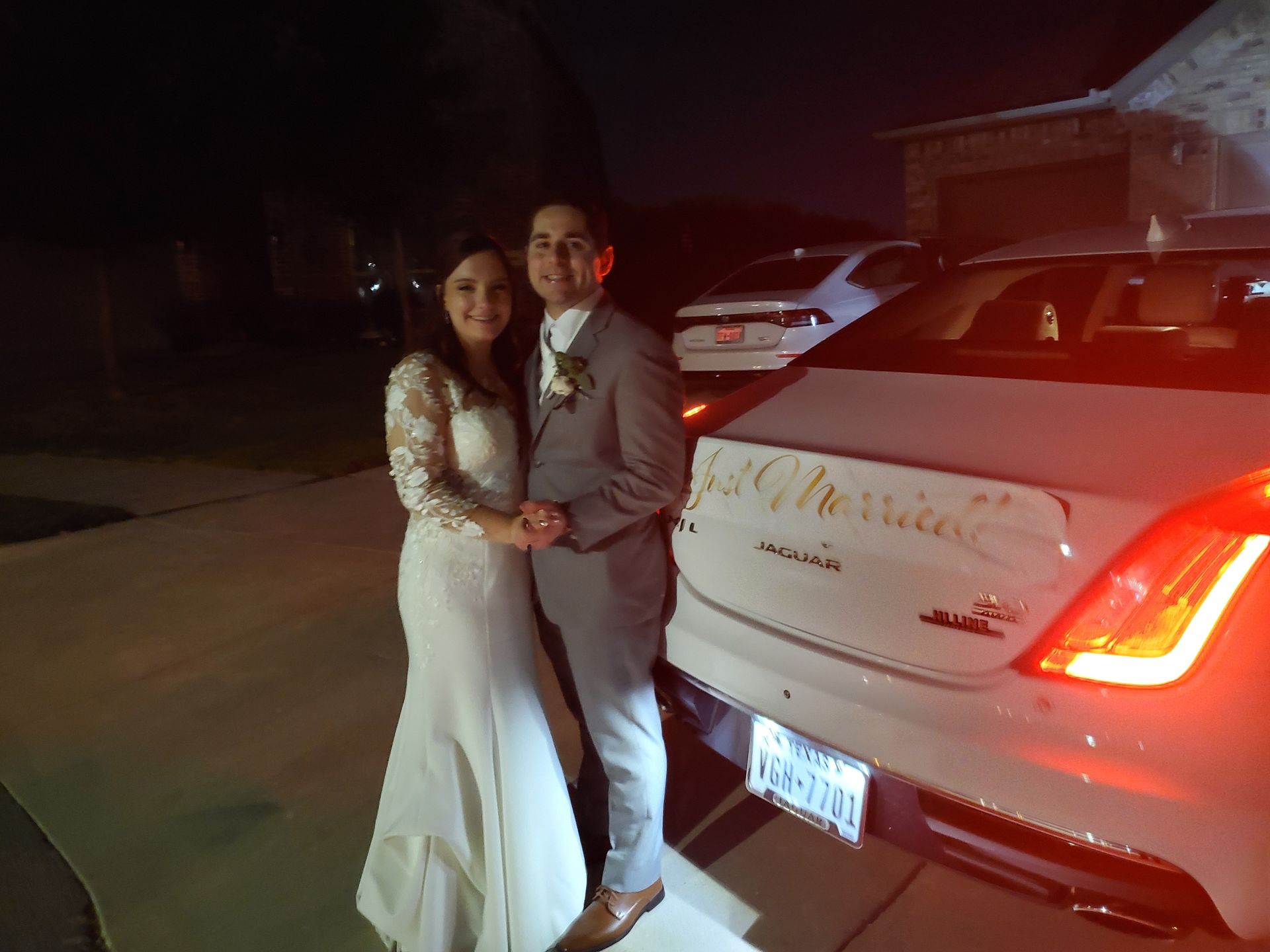A bride and groom are posing for a picture in front of a wedding car.