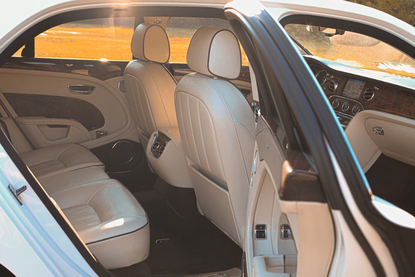 The back seat of a white car with the door open.