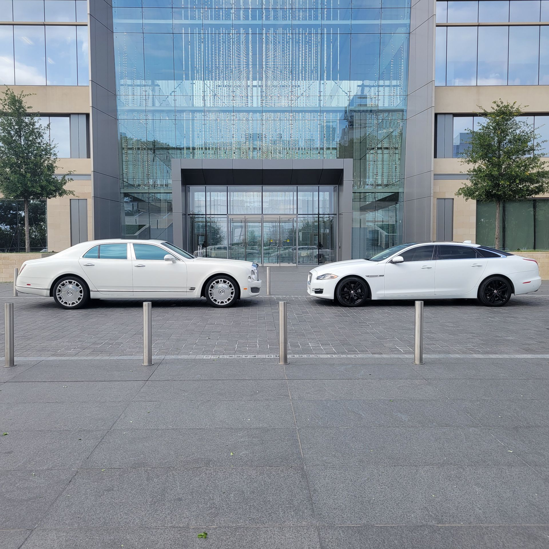 Two white cars are parked in front of a building