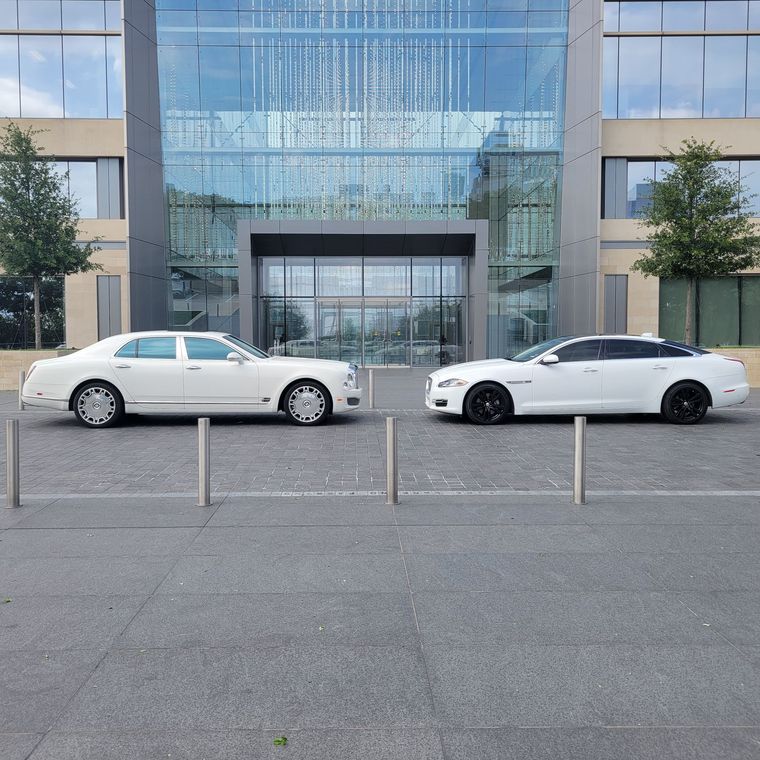 Two white cars are parked next to each other in front of a building.