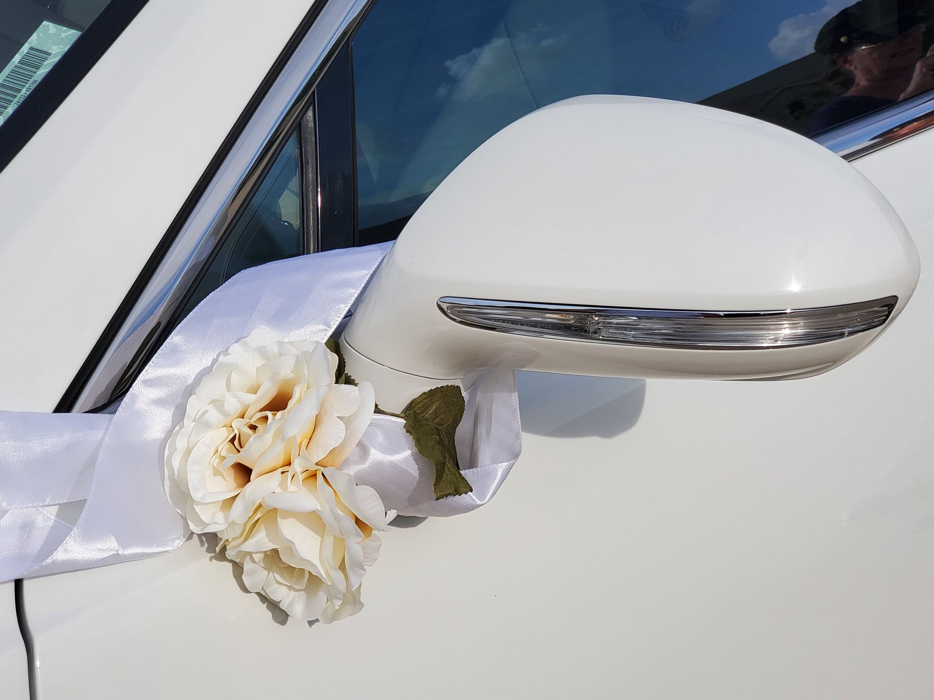 A white car with a flower on the side mirror