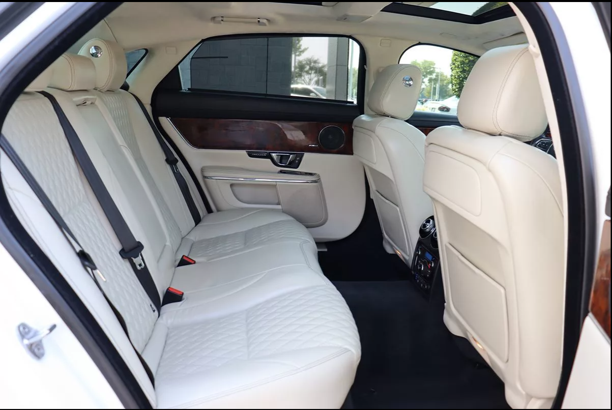 The back seat of a white car with tan leather seats