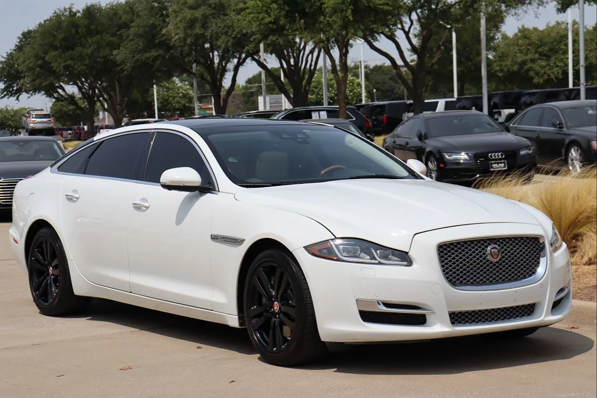 A white jaguar x type is parked in a parking lot.