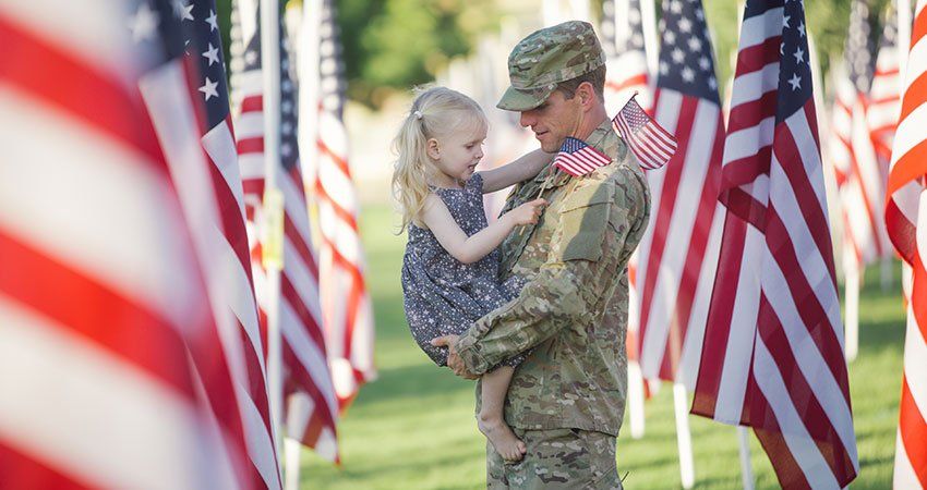 man in military uniform holds young girl