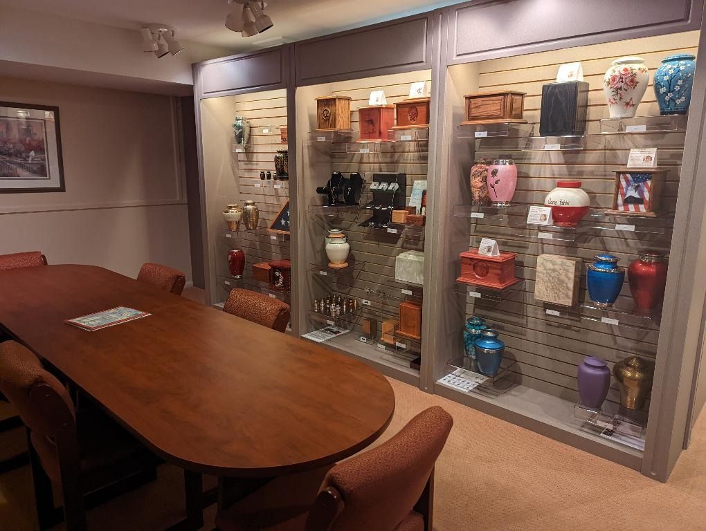 Funeral home consultation room, with display cases of urns and a table with chairs.