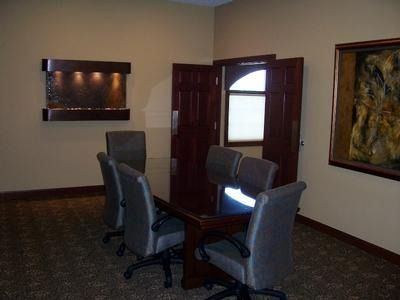 Office with meeting table, chairs, water feature, open double doors, and artwork on walls.
