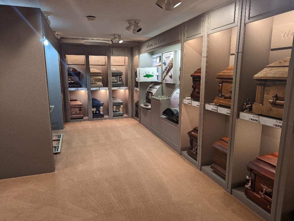 A display room with various caskets in wall niches, neutral color palette, and spotlights.
