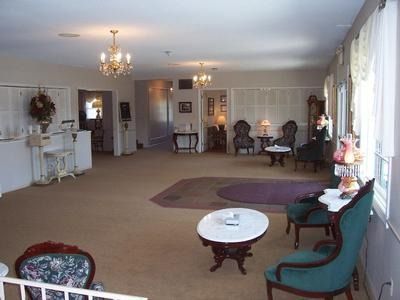 A spacious room with chairs, tables, and chandeliers, possibly a waiting area or lounge.
