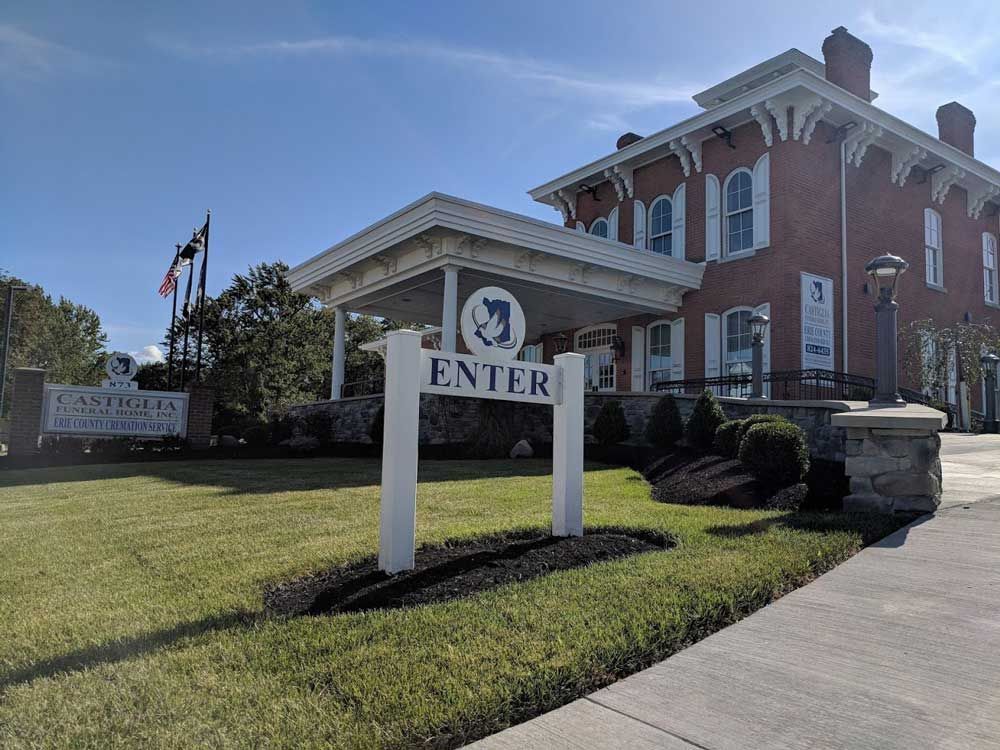 A sunny day view of a red brick building with a covered entrance and an 