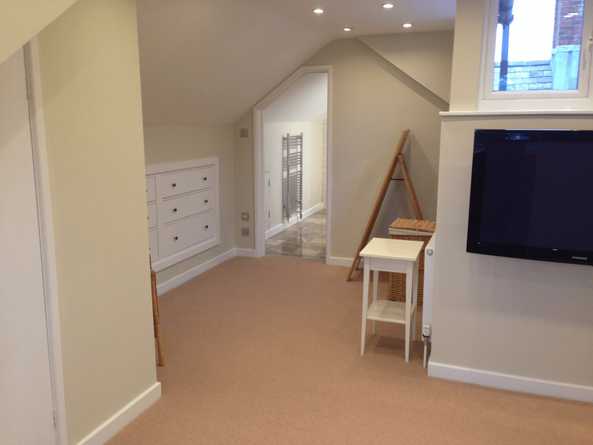 Bedroom with wall mounted TV and en suite in background