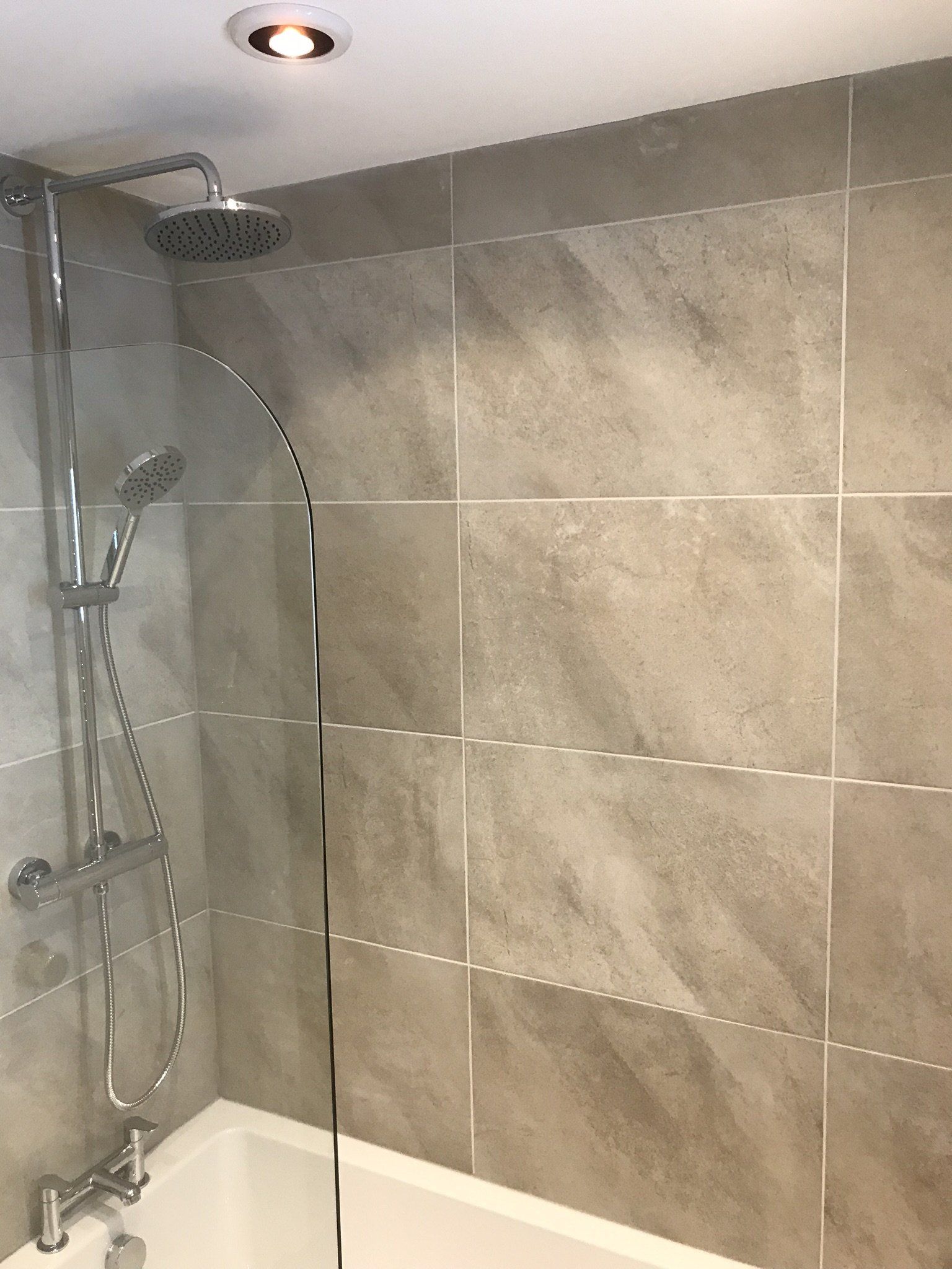 close up of large grey marble effect tiles over bath