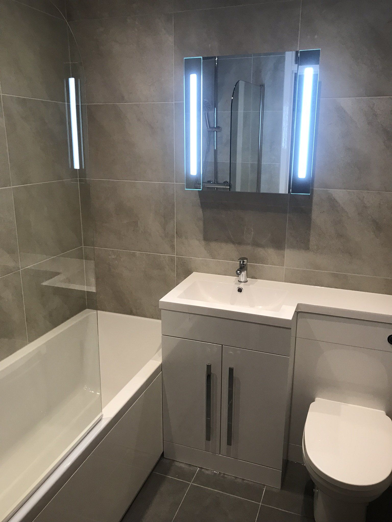 illuminated mirror above white vanity unit