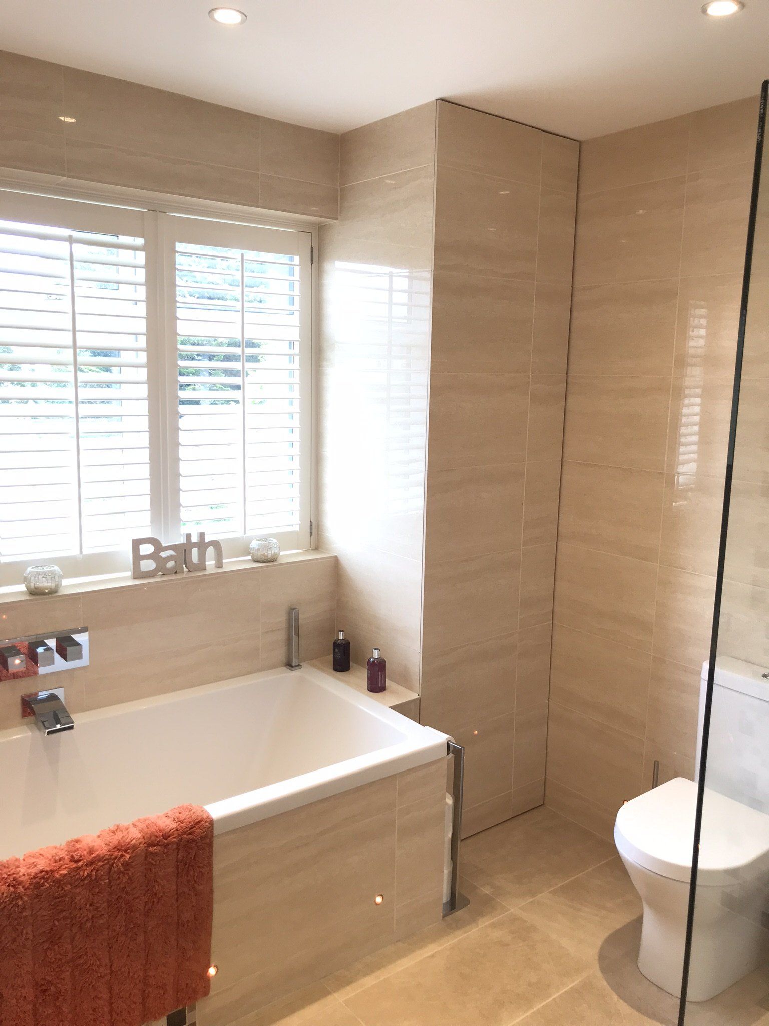 bathroom with plantation style shutters and faux marble tiles floor to ceiling
