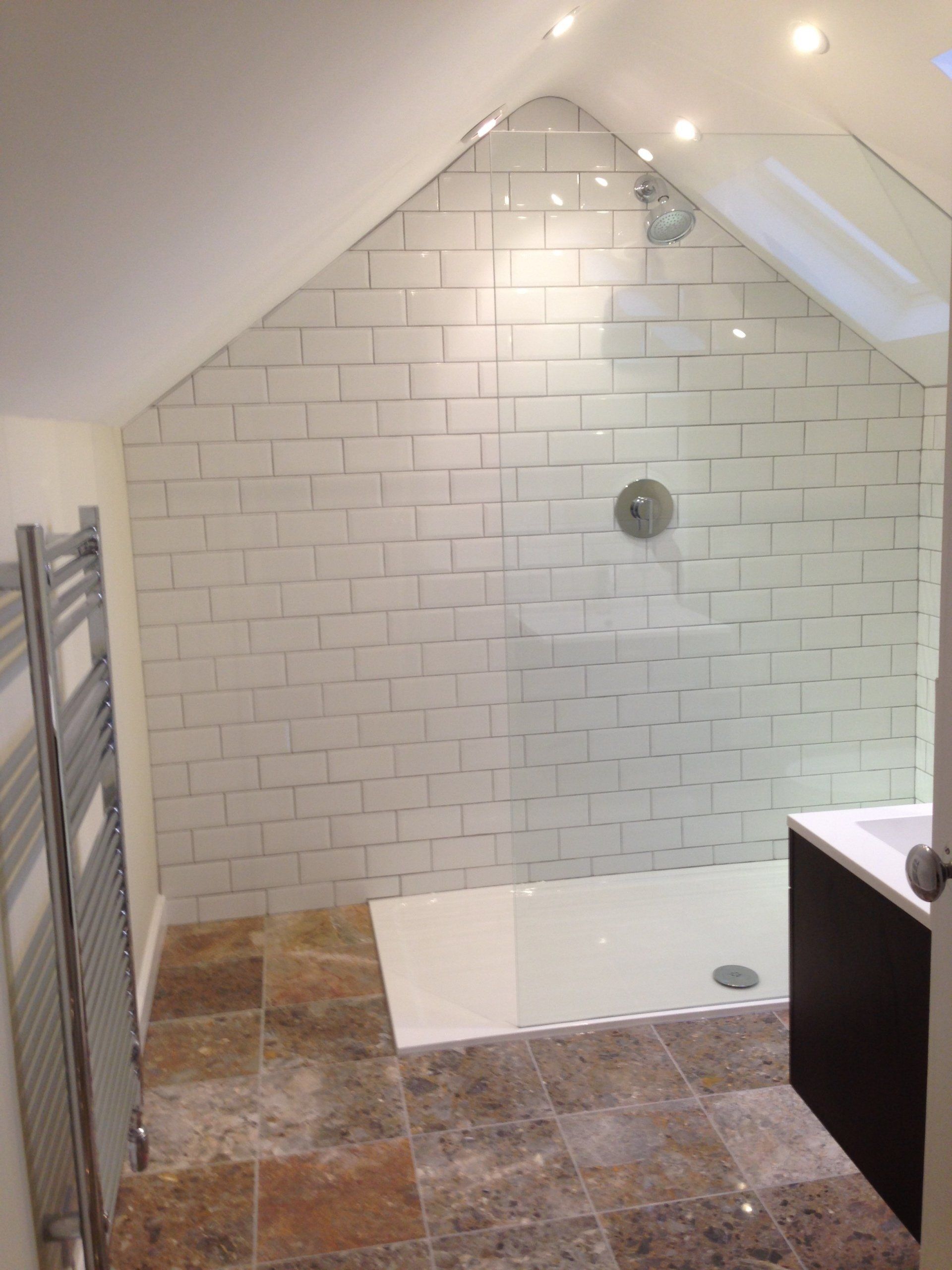 large new walk in shower with white tiled wall and granite floor tiles