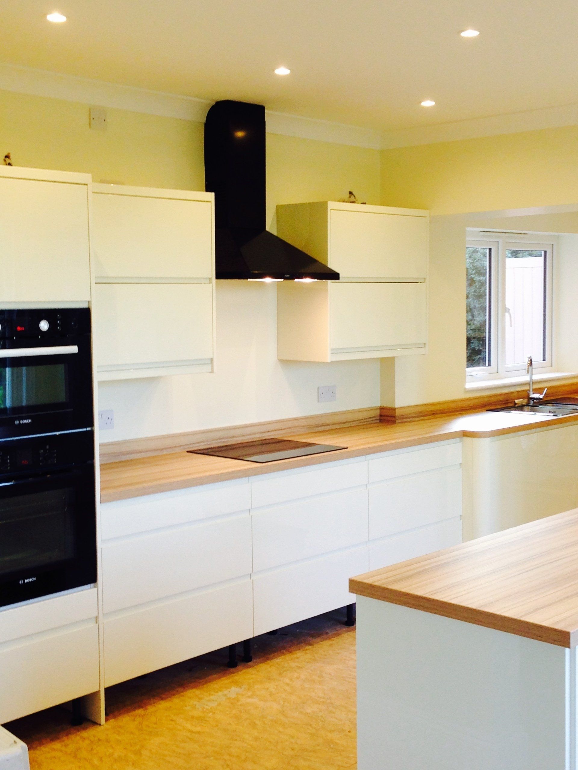 sleek new white kitchen with handleless units and black extractor hood