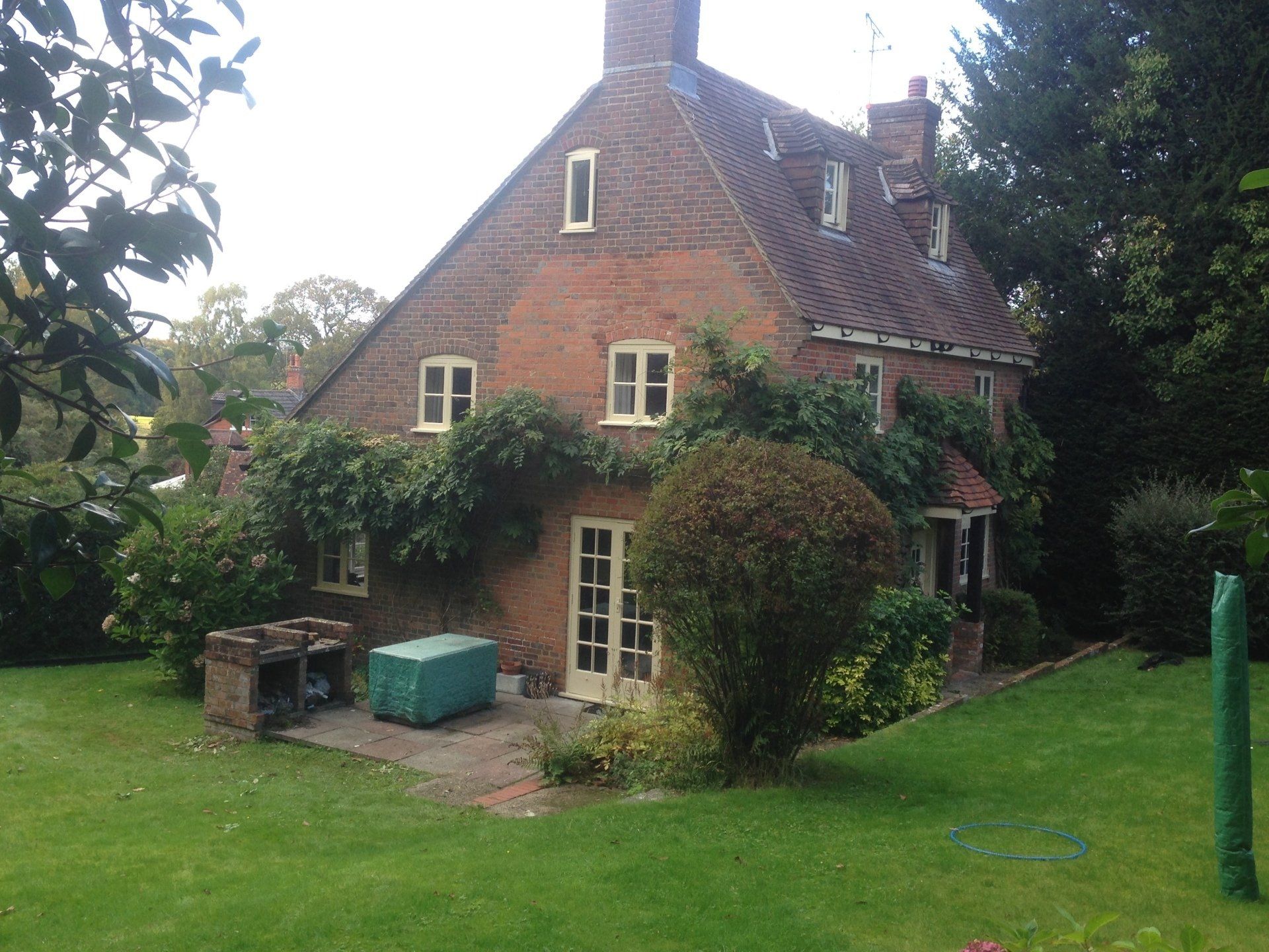 side view of pretty wisteria covere house with French doors and brick BBQ