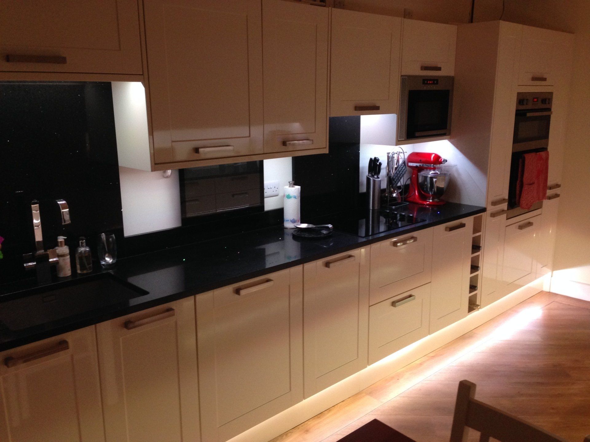 long view down cream gloss cabinets with illumination under units and at floor level
