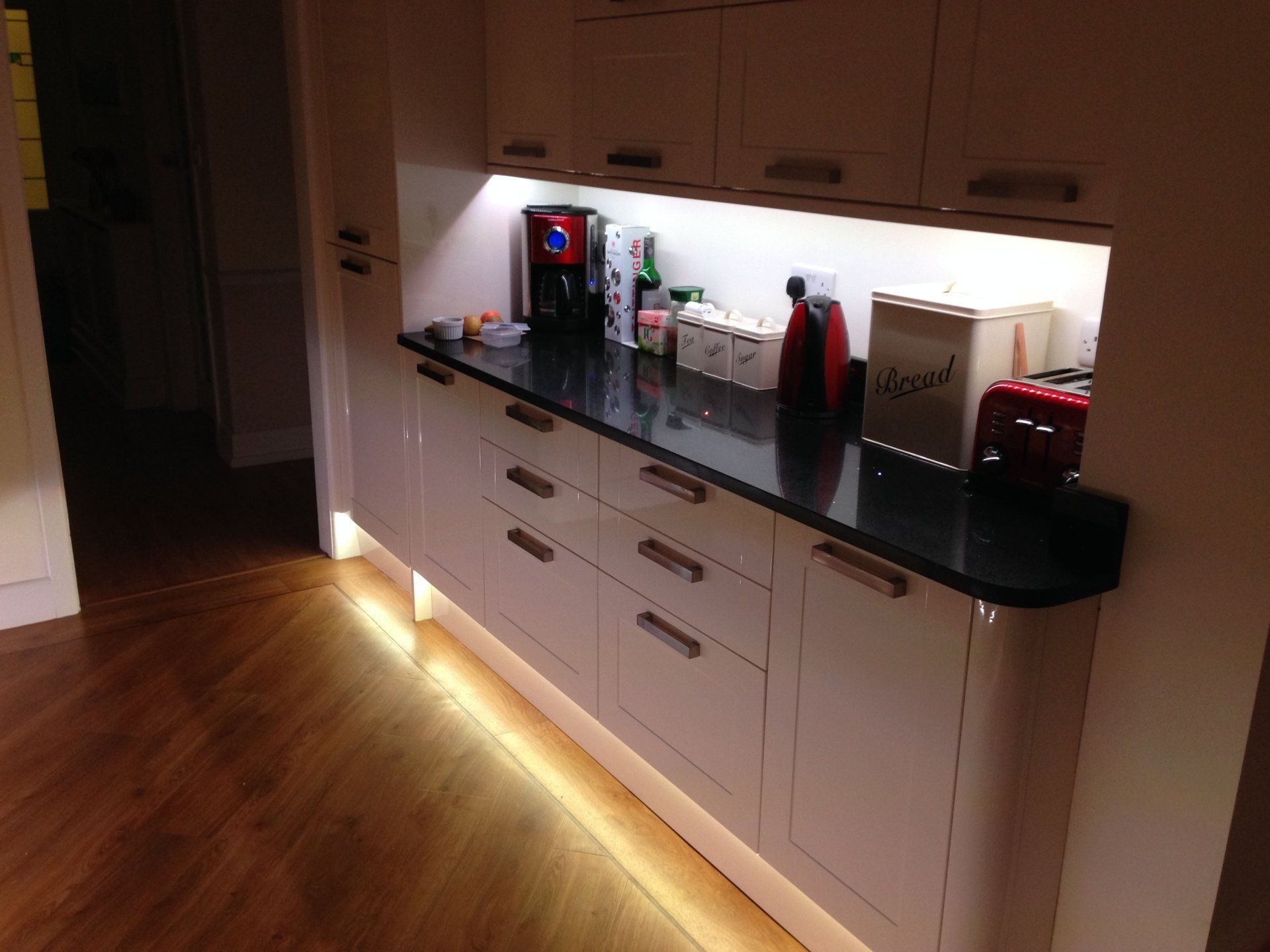 cream gloss cabinets with illumination under units and at floor level