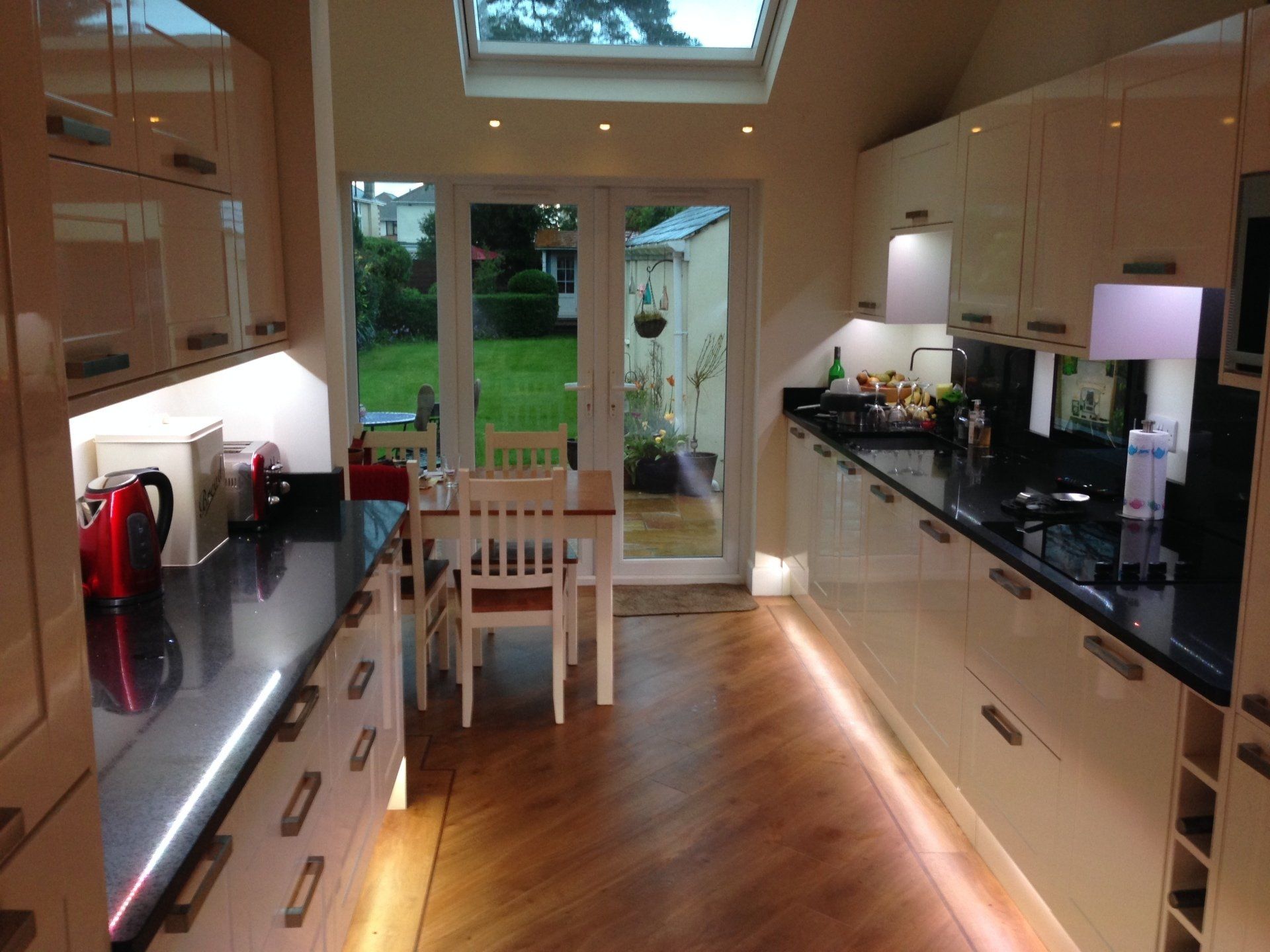 new kitchen with roof window and illumination under cream gloss cabinets
