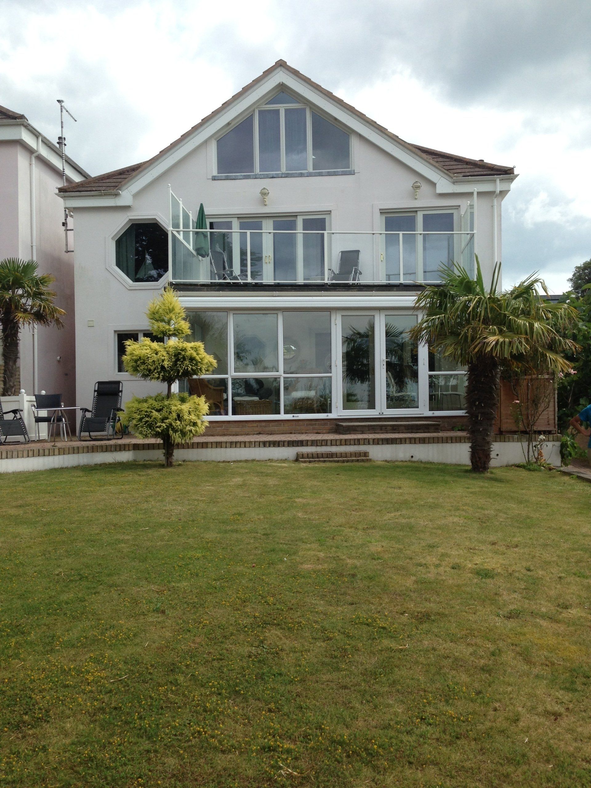 rear view of large home with downstairs floor to ceilings windows and doors and terrace above