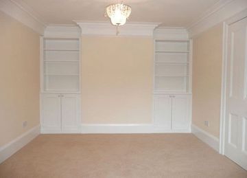 cream walls and carpet in room with built in dressers