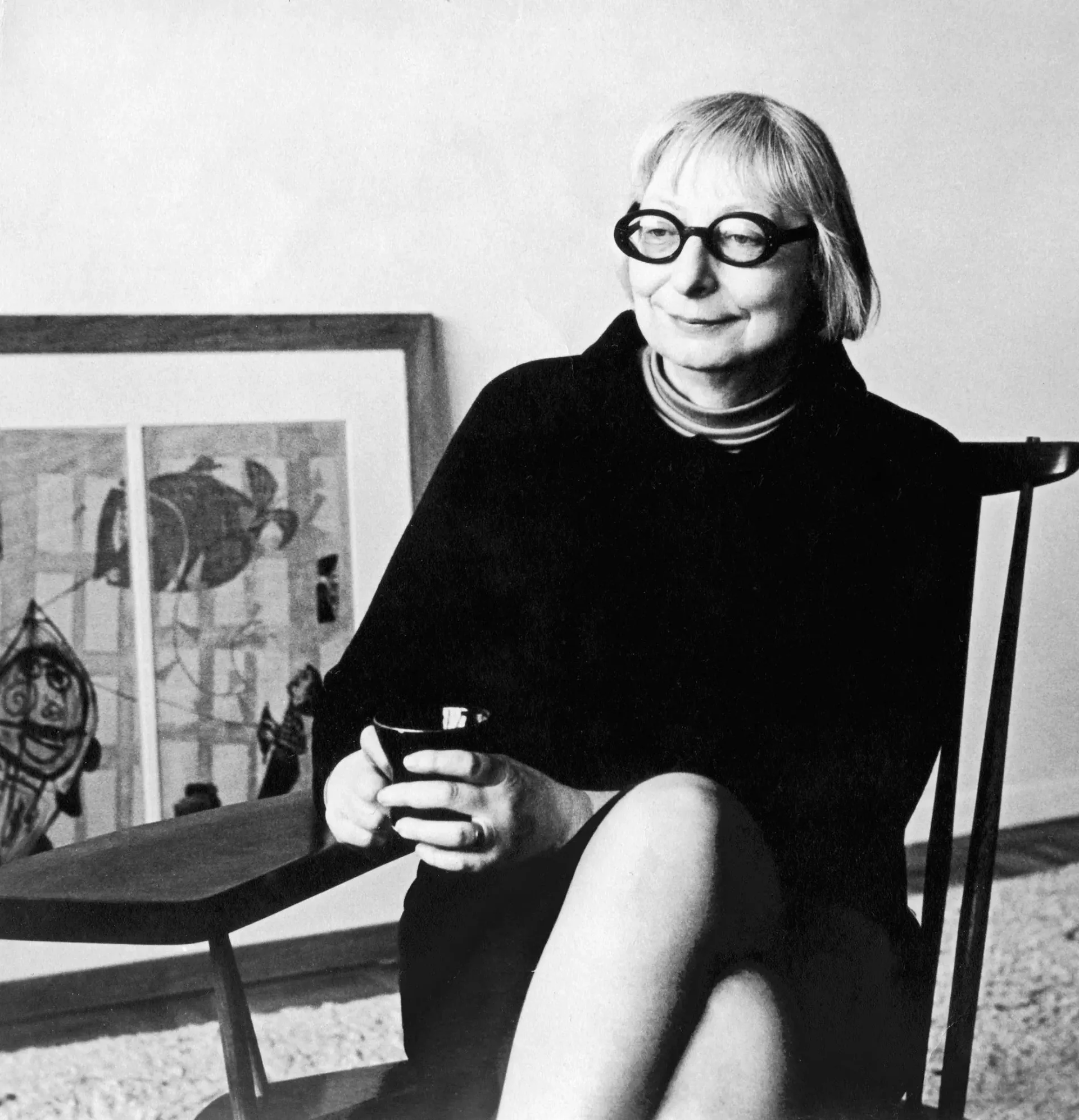 Jane Jacobs sitting in a chair holding a cup of coffee