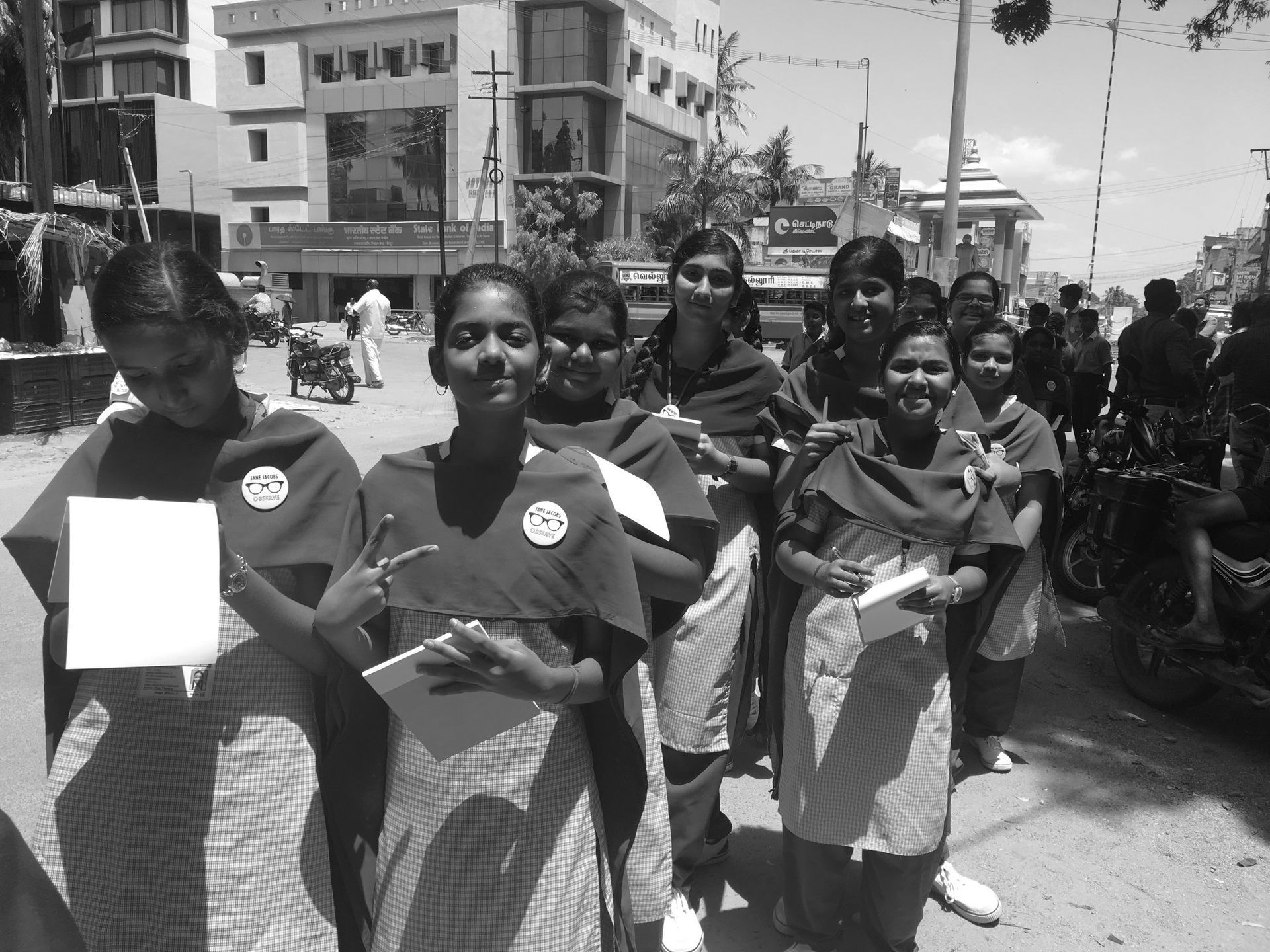 A black and white photo of a group of girls walking down a street in India