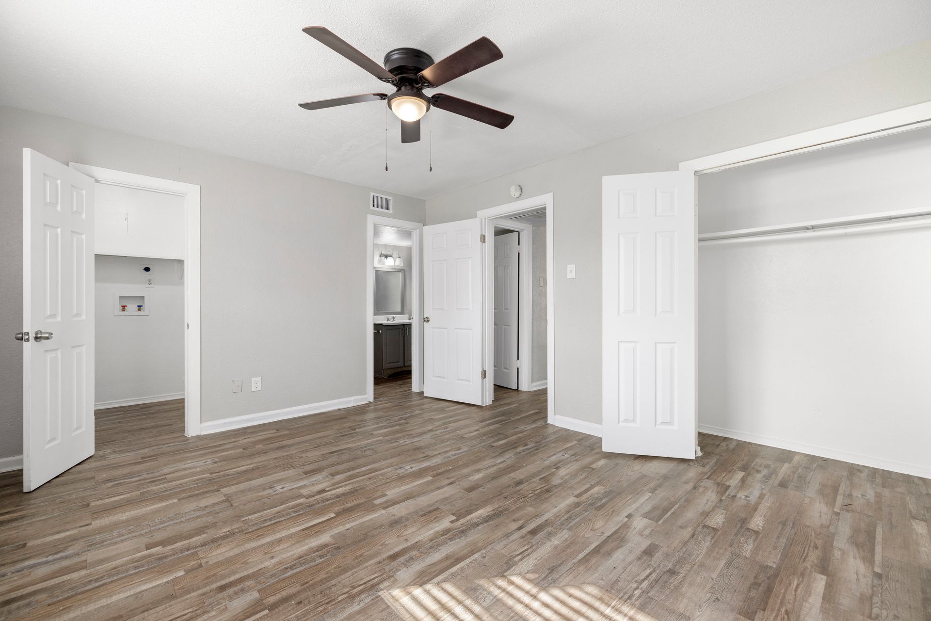 An empty living room with hardwood floors and a white door at Senita Apartment Homes in Dallas, TX!