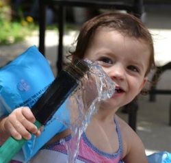 child interacting with water from a hose
