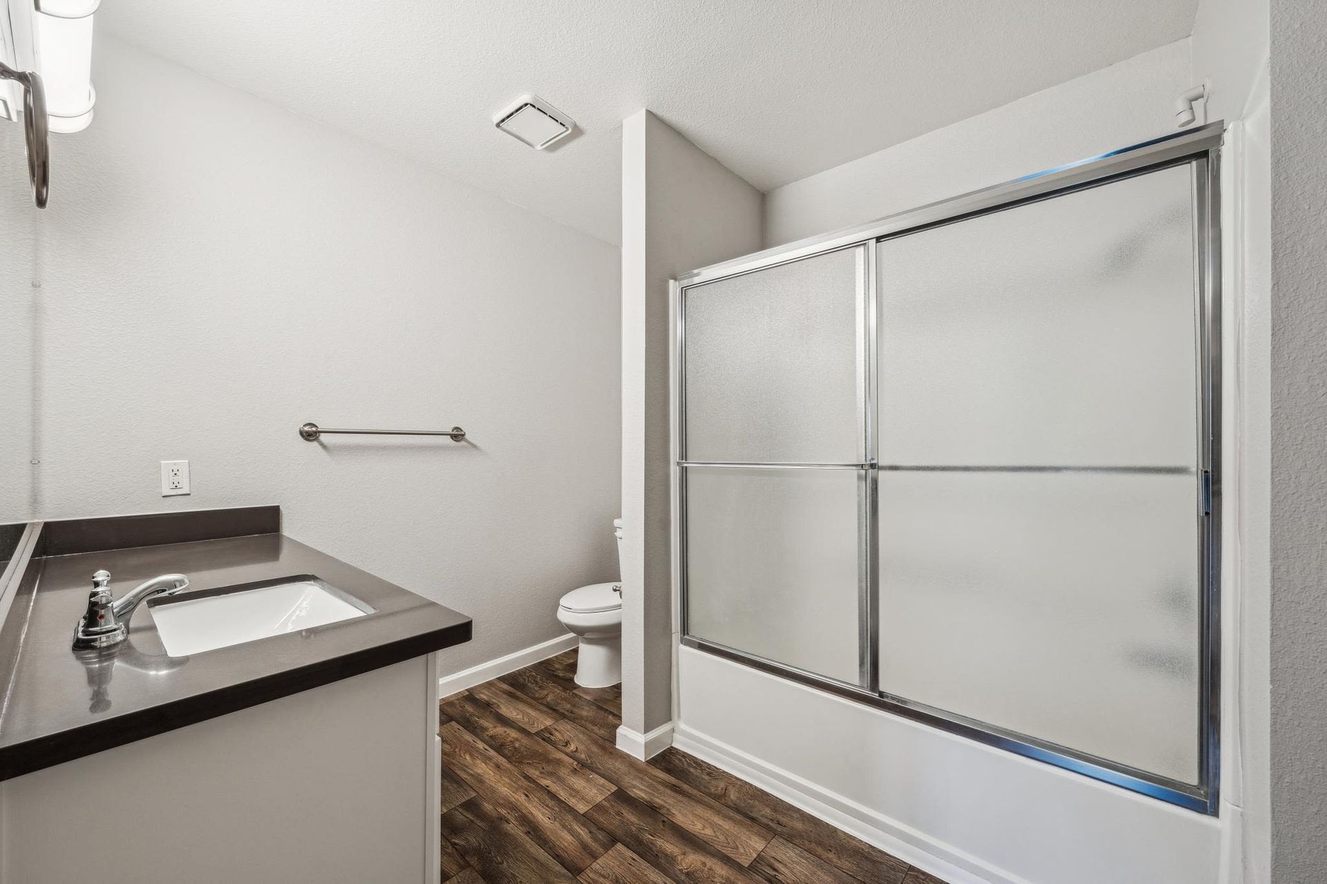 Bathroom with a single vanity, sink, toilet, and frosted sliding shower door.