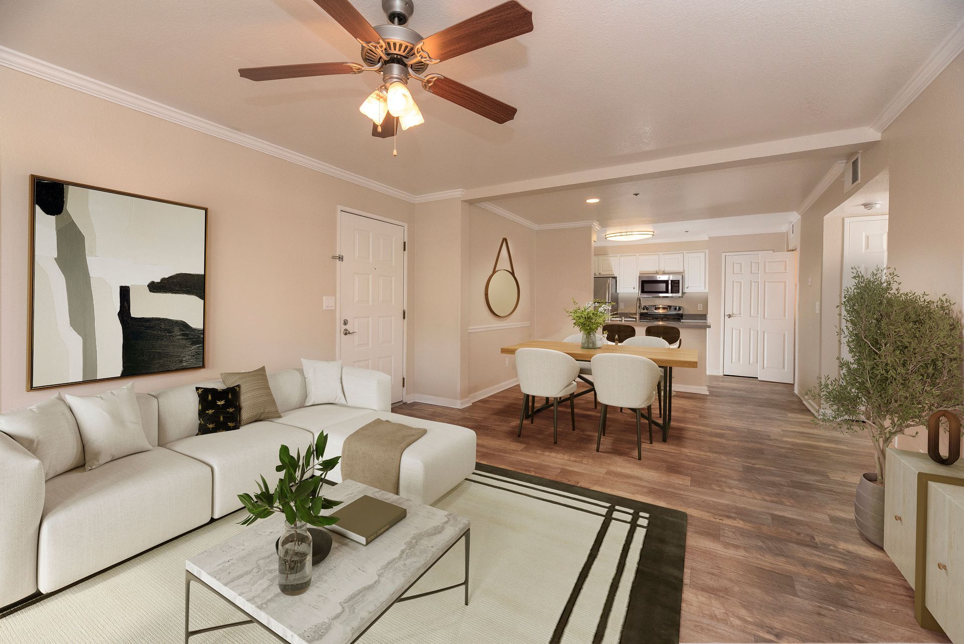 Open living area with a white sectional sofa, coffee table, dining table, and kitchen in the background.