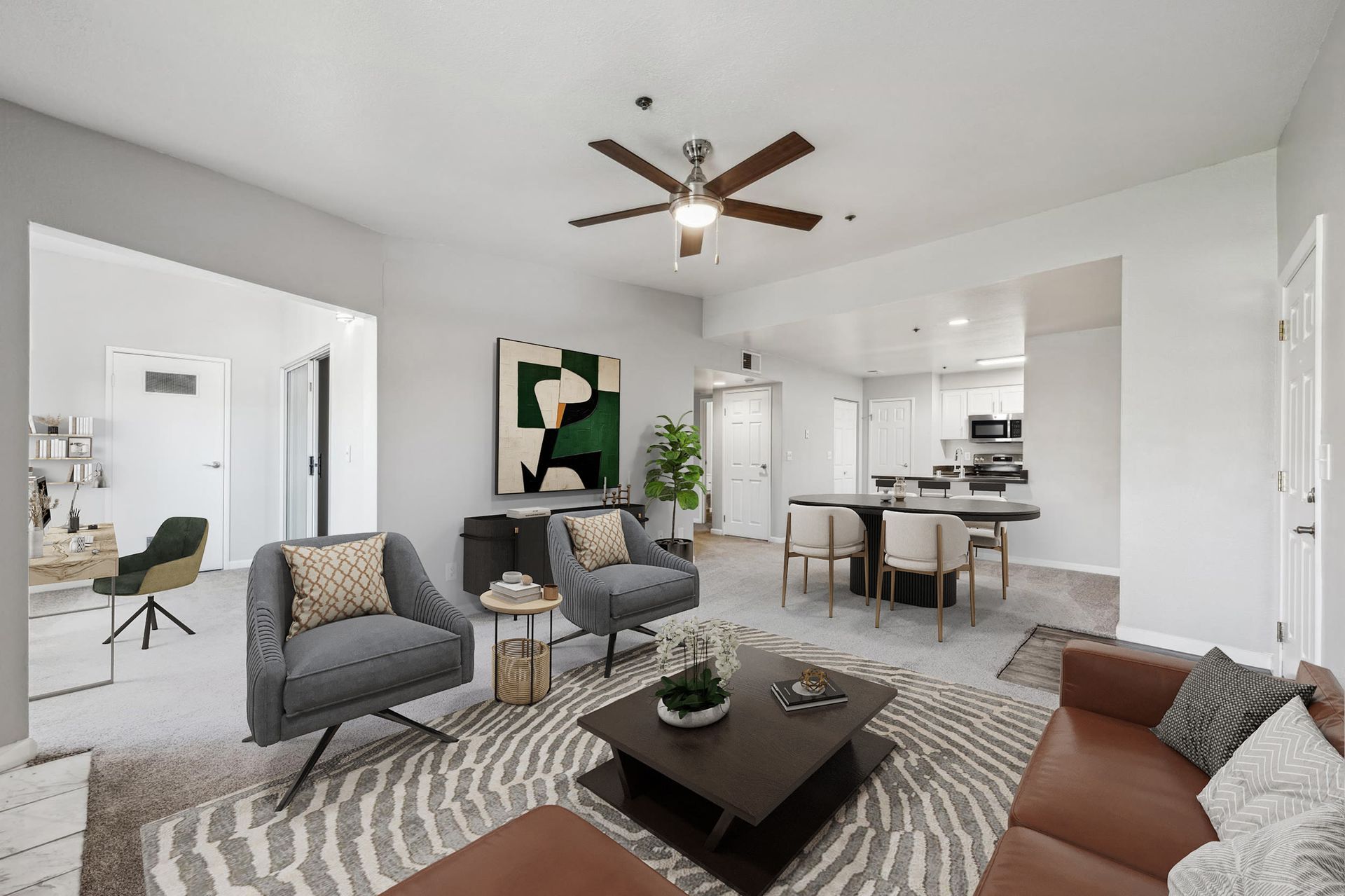 Open-concept living room with gray seating, a patterned rug, and a dining area near the kitchen.