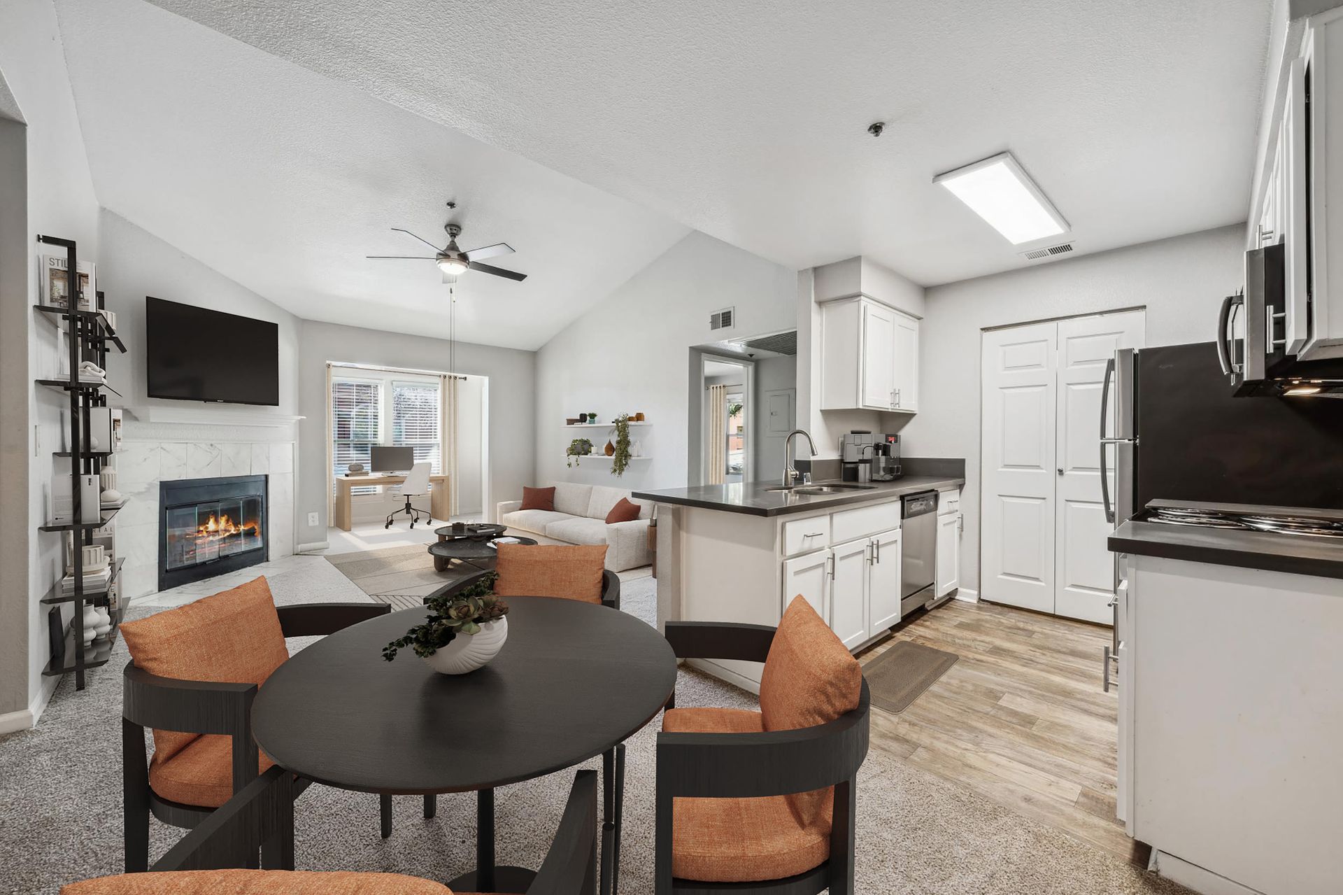 Open-concept living area with a fireplace, dining table, and a modern kitchen.
