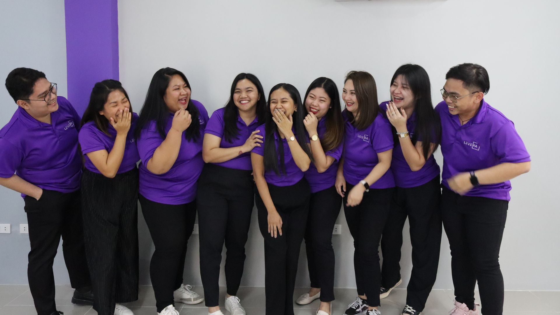 A group of people wearing purple shirts and black pants are posing for a picture.